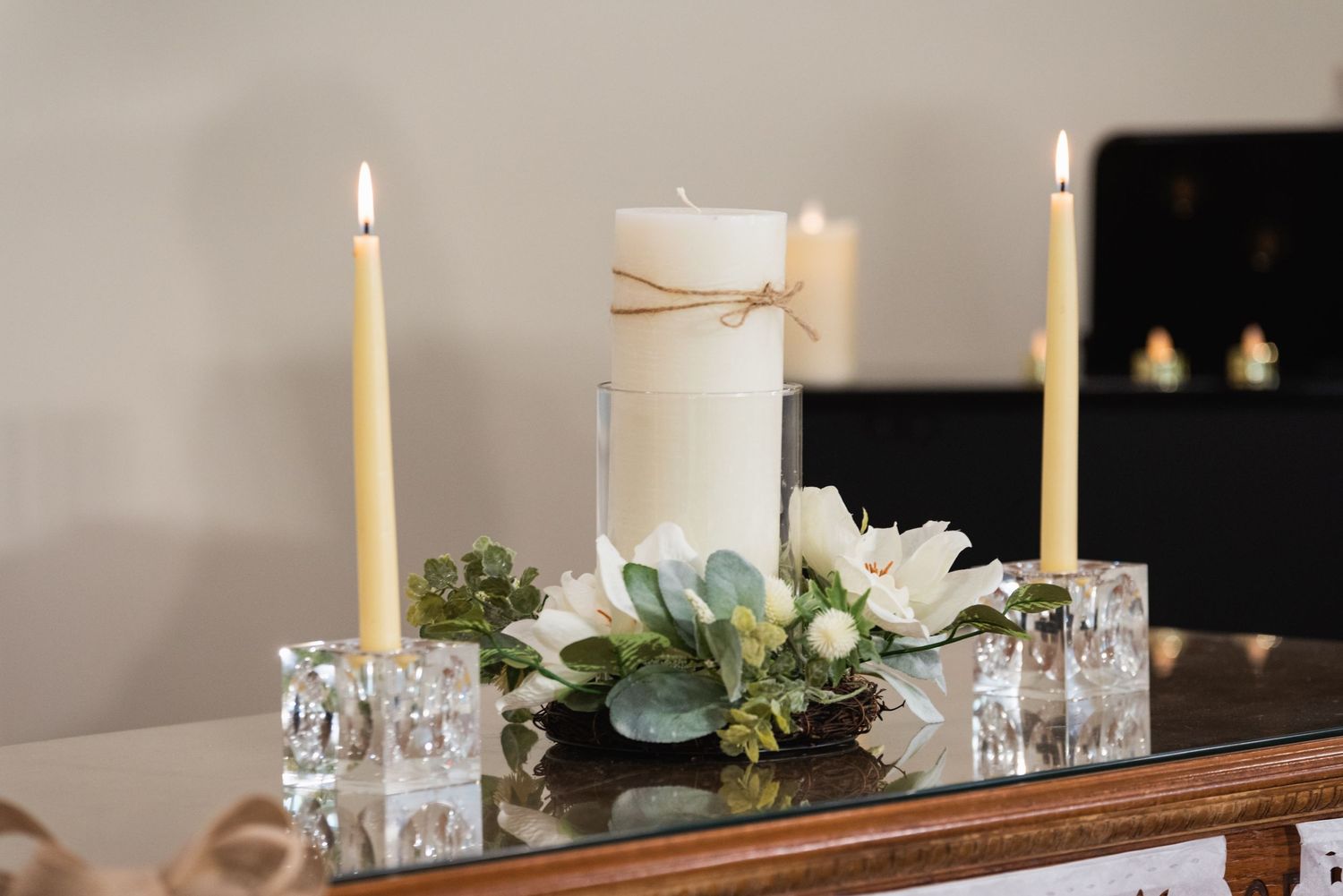 An elegant table setting with white candles and floral centerpiece for a special occasion.