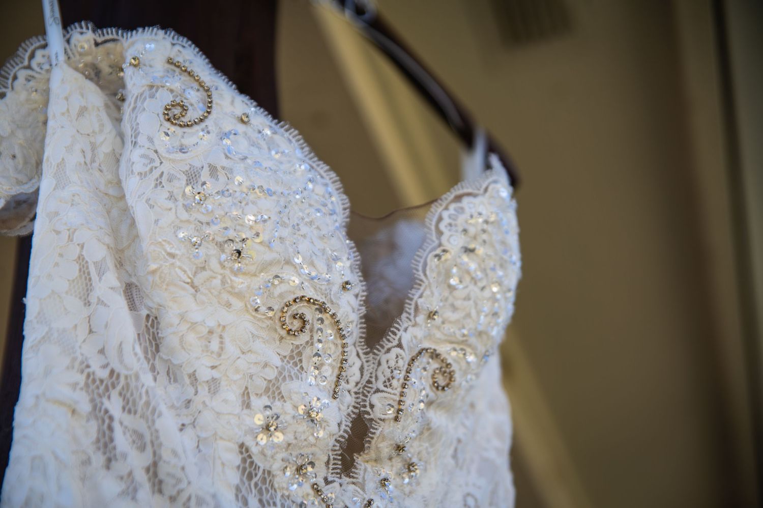 Close-up detail of intricate beaded lace pattern on white wedding dress bodice.