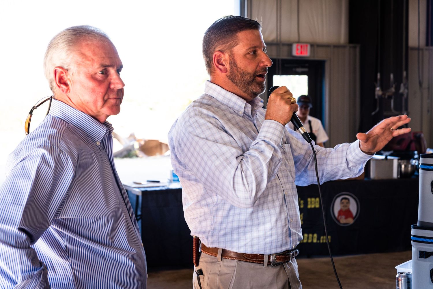 Two speakers present during an indoor business event with one holding a microphone.