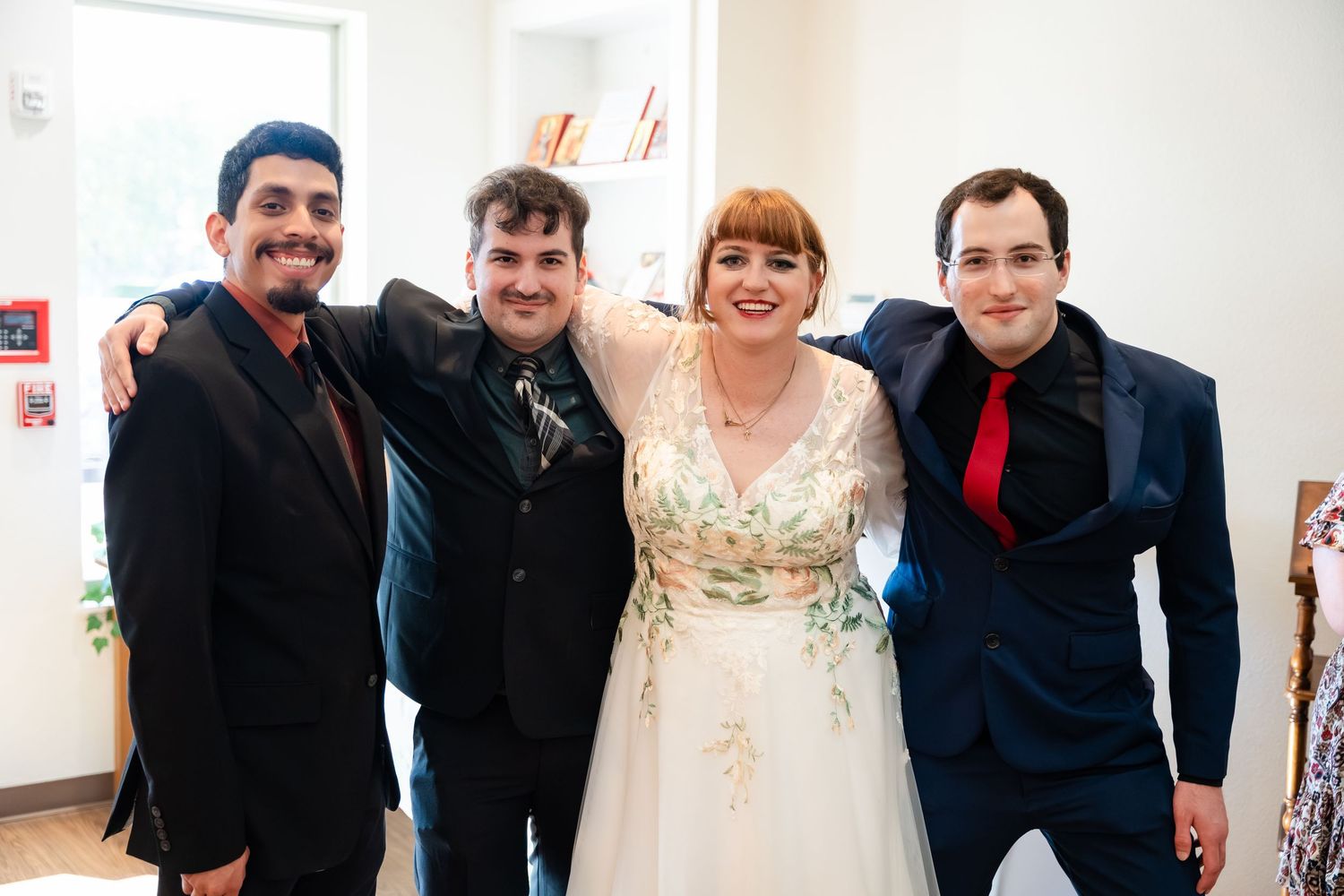 A series of wedding photos showing guests and the wedding party posing together in a white room with artwork on walls.