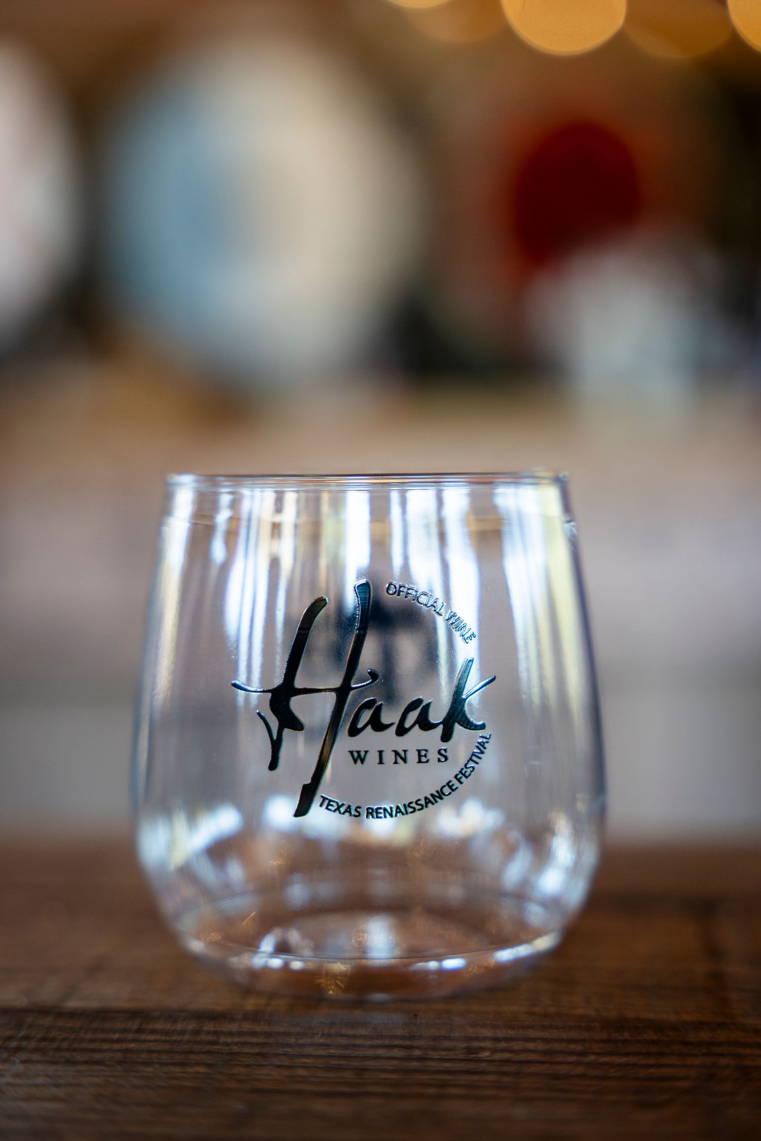 A series of clear wine glasses with the Husch Winery logo displayed in a row on a wooden surface.