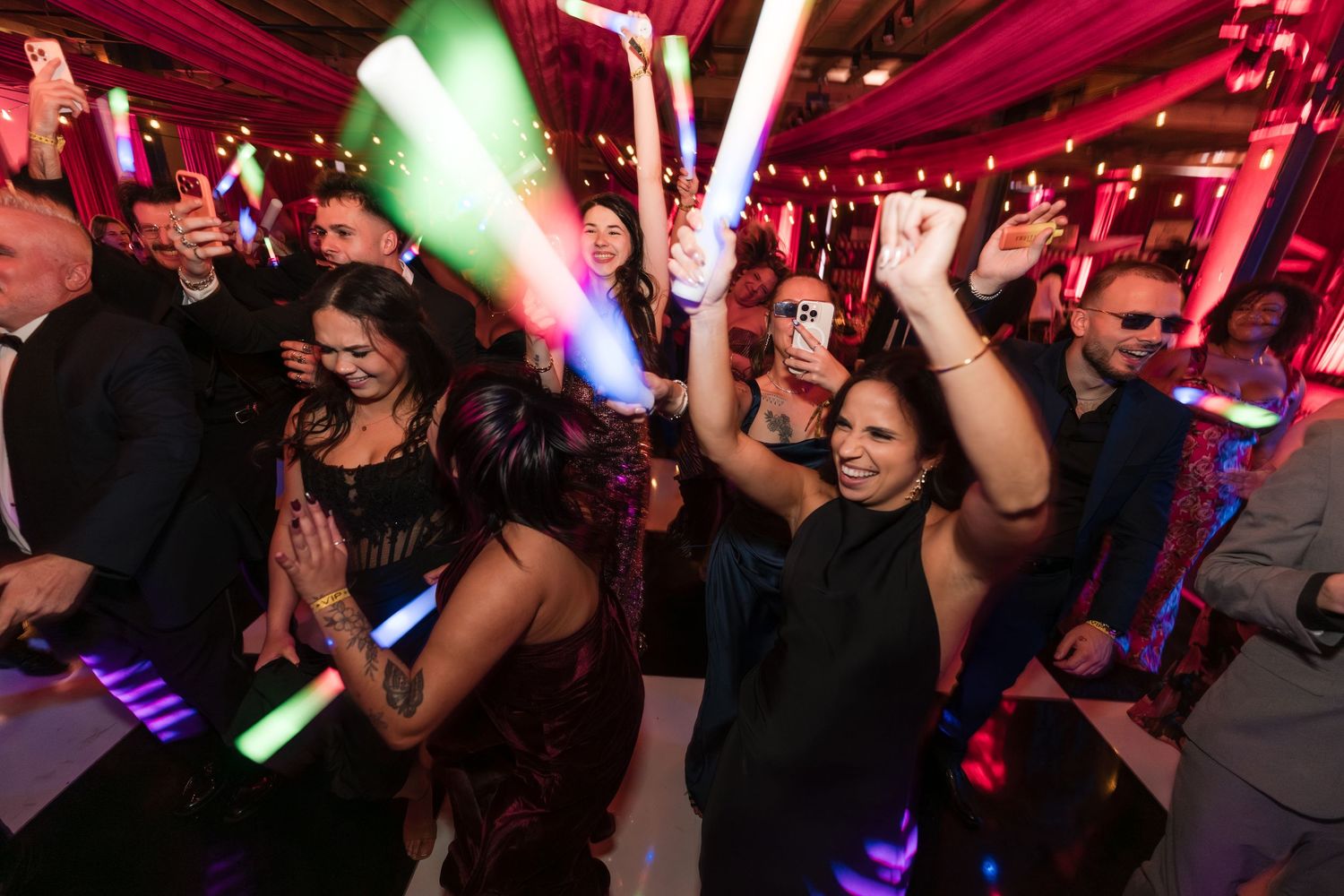 People dancing and having fun at a nightclub with colorful red and green lighting effects.
