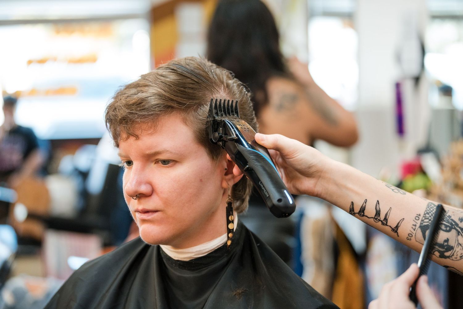 Professional hairstylist using scissors and comb to cut client's hair in modern salon.