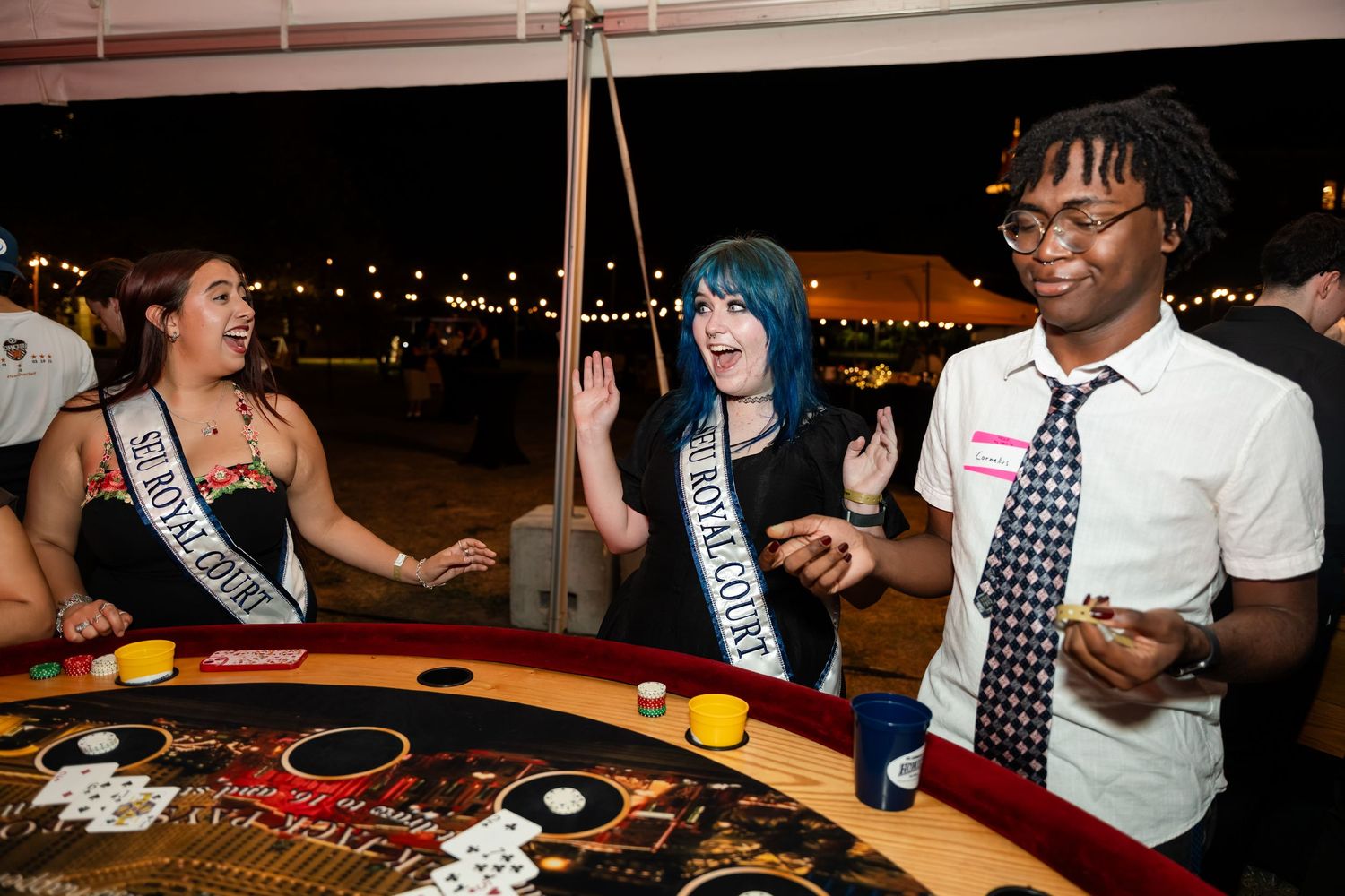 People playing casino games at tables with dealers and chips during a social event.