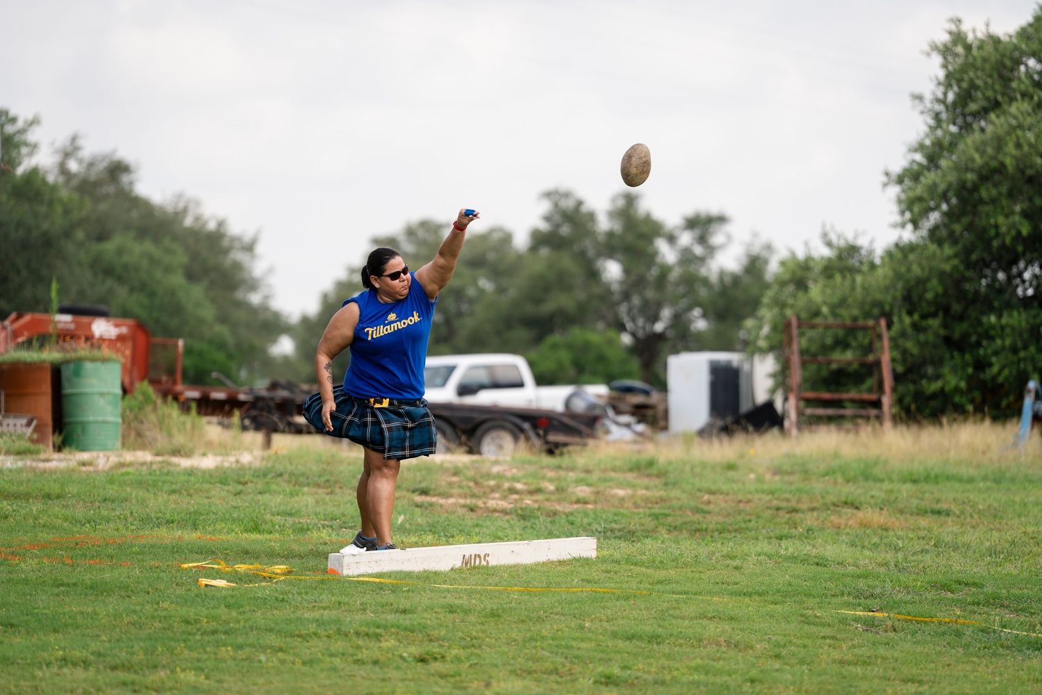 A sequence of action shots showing someone throwing a football across a grassy field on a sunny day.