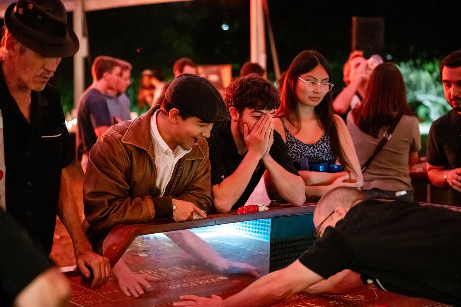 People sitting at tables in a dimly lit venue with red ambient lighting.