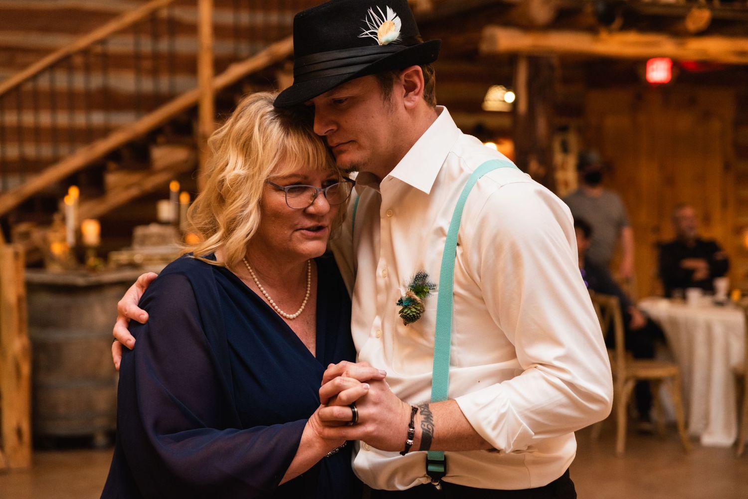 A tender moment between two people dancing at a rustic barn wedding reception.