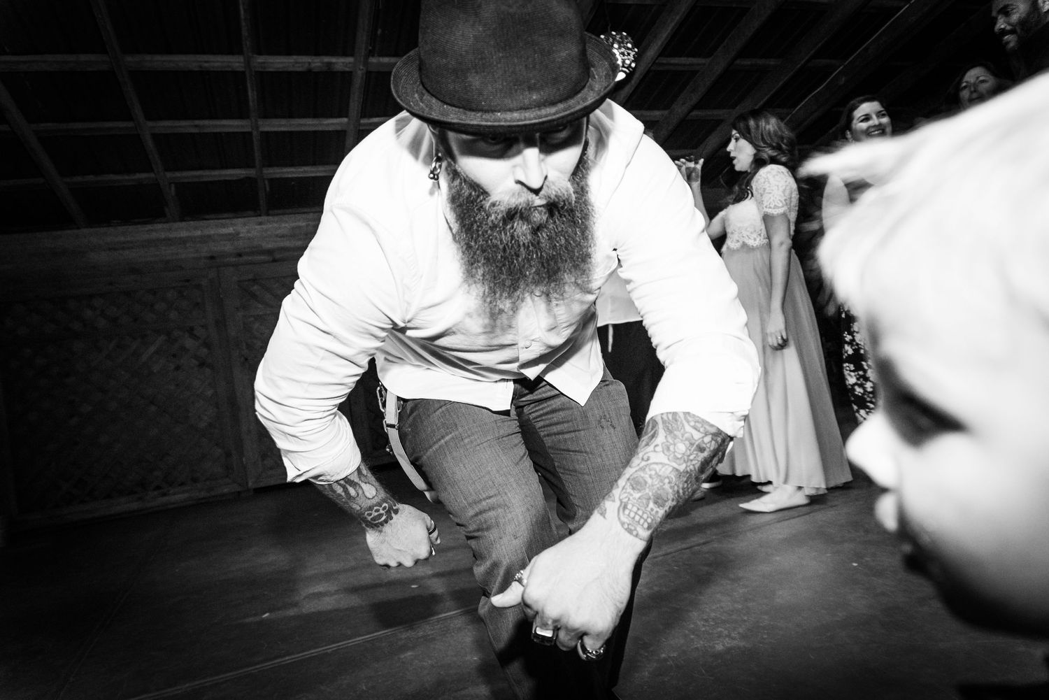 Person with beard and hat showing off dance moves on reception floor.