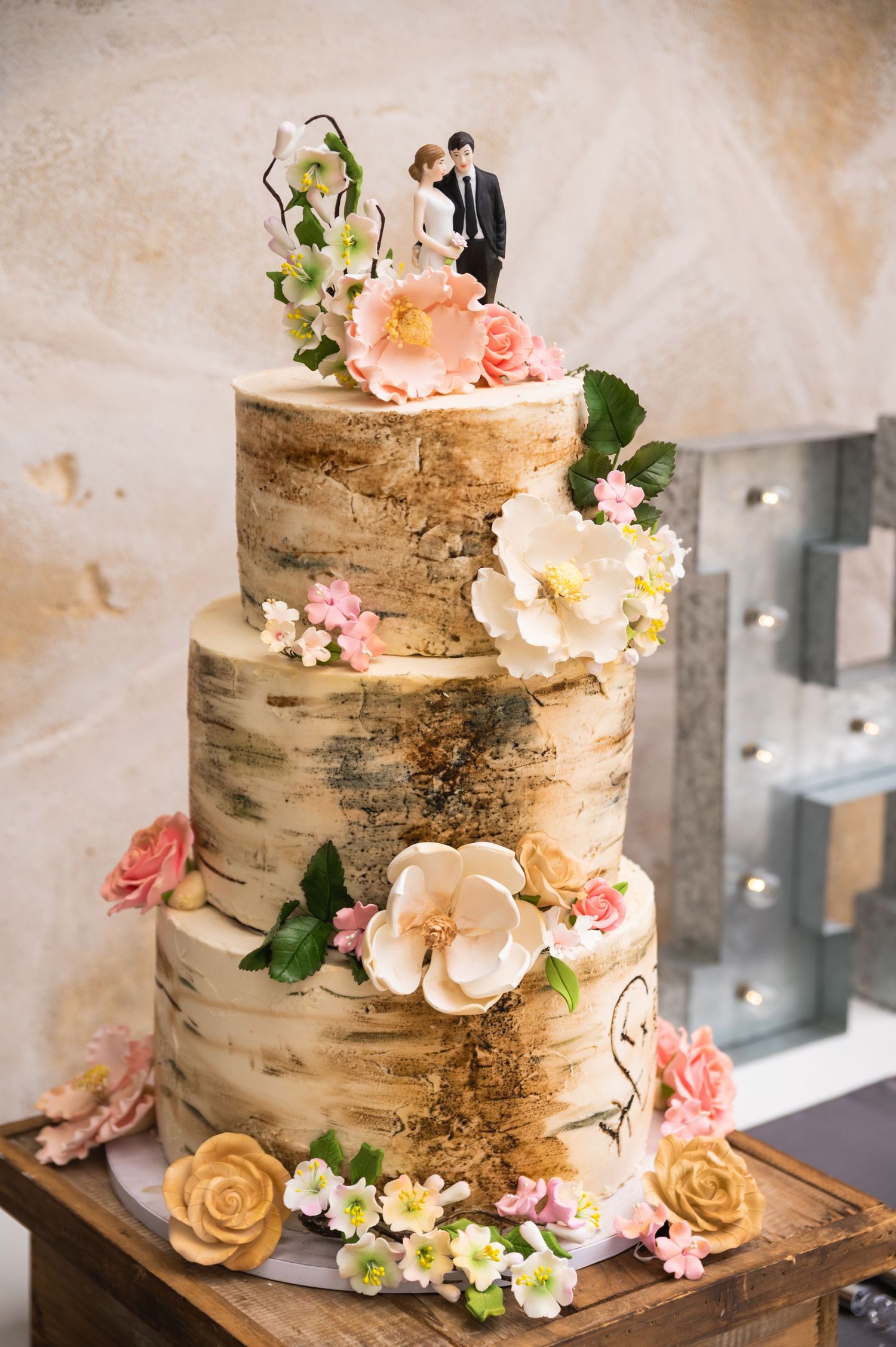 Rustic birch-themed wedding cake decorated with pink and white flowers.