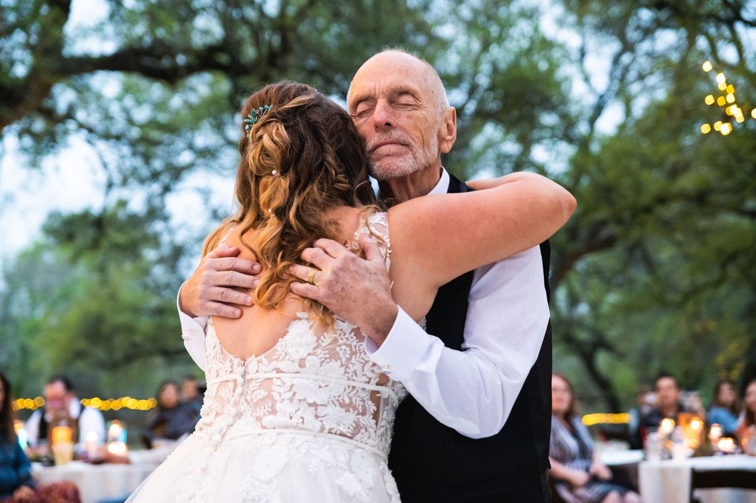 Dancing couple embraces during an emotional moment at twilight outdoor wedding reception.