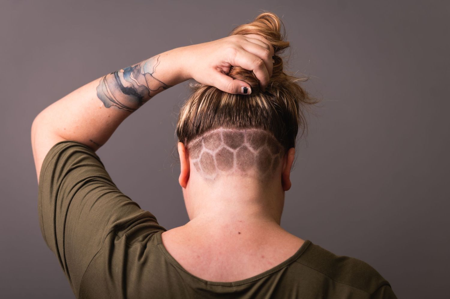 Back view of geometric undercut hair design with hand styling.