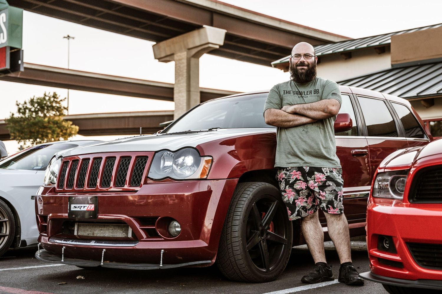 Modified red Jeep Grand Cherokee SRT with custom wheels parked at a car meet.