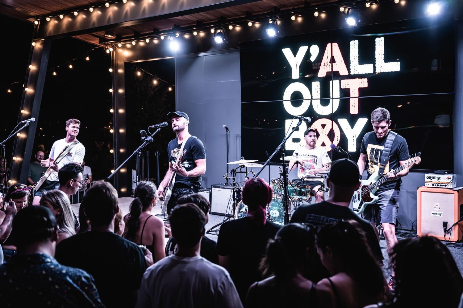 A live concert performance on stage with Y'all Out Boy signage and crowd in foreground.