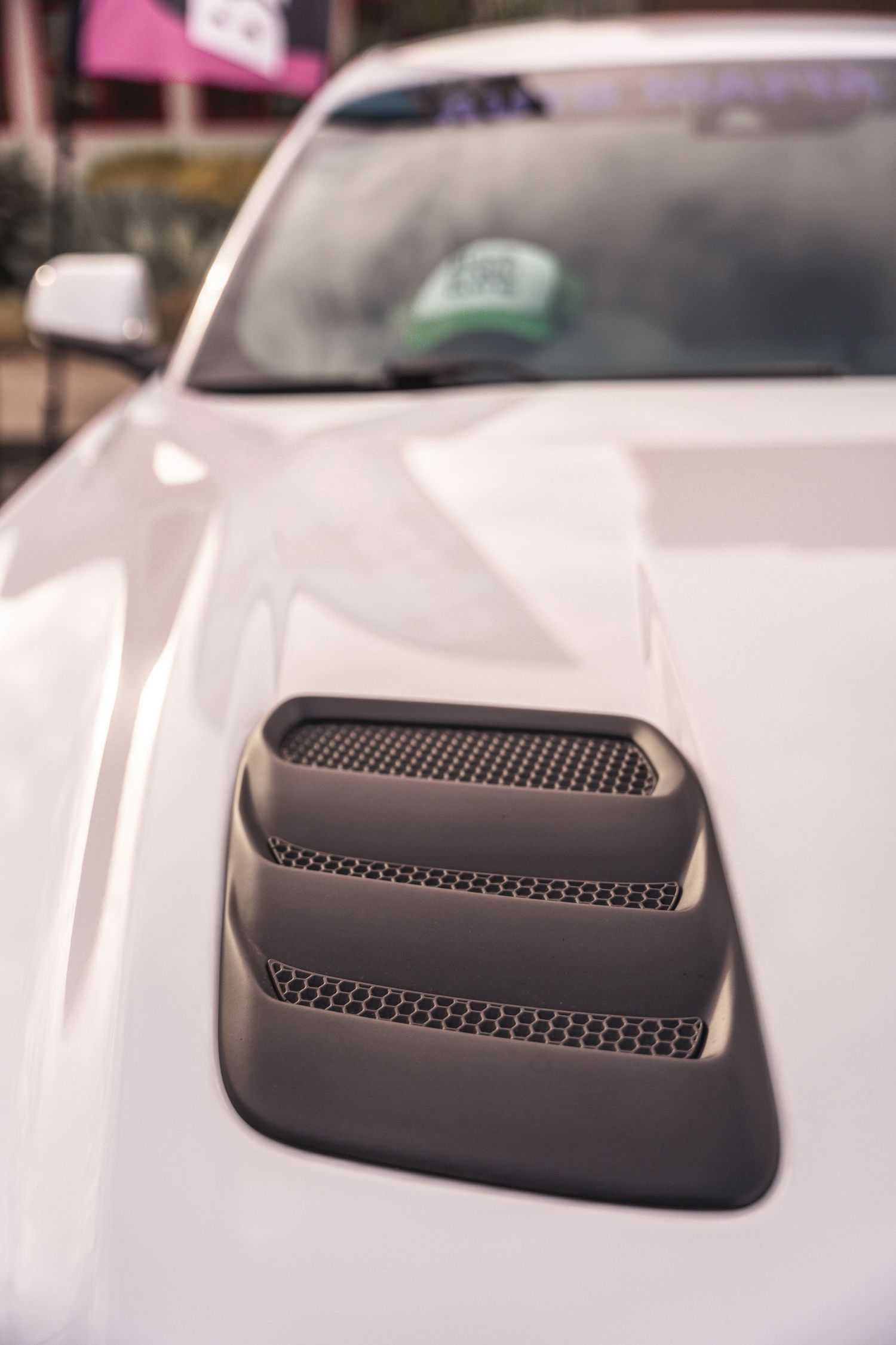 Close up of a white car hood with black ventilation grilles.