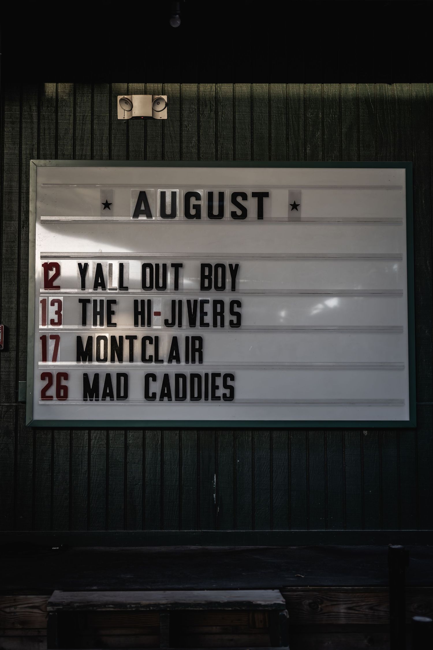 Black and white event board listing August performances including Fall Out Boy and other bands.