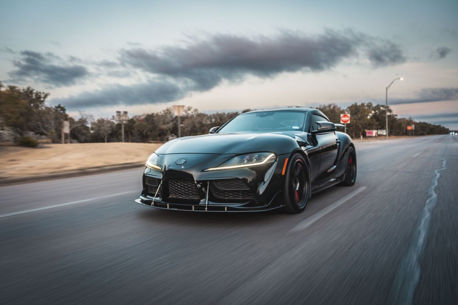 Modified Toyota Supra with aggressive aero kit photographed during sunset.