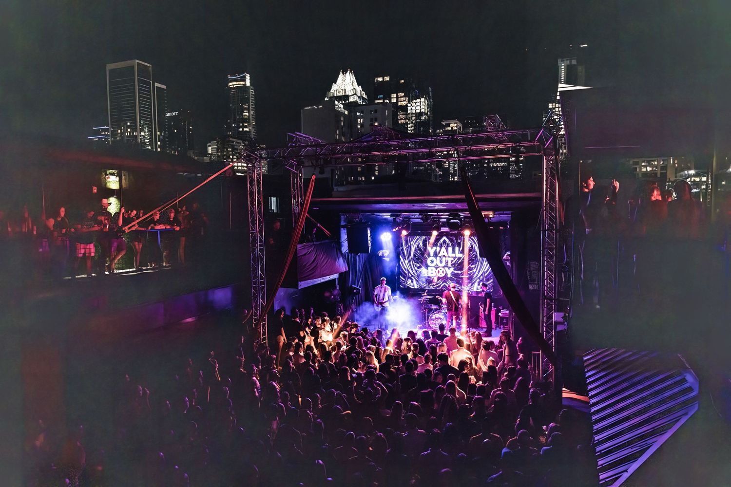 Outdoor concert venue at night with city skyline visible in background.