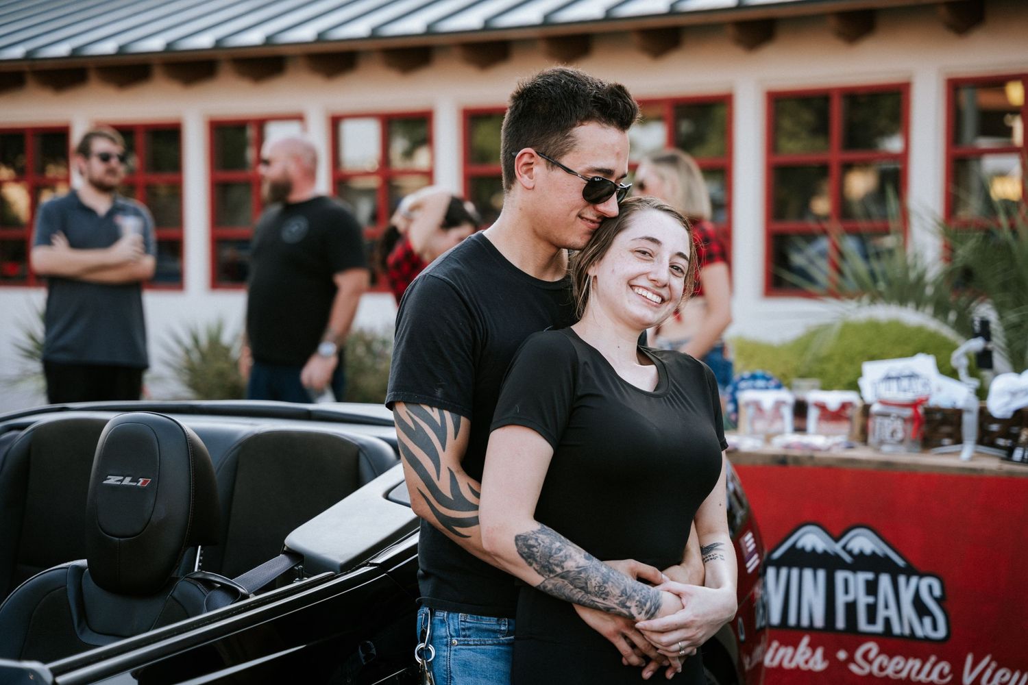 Car enthusiasts gathered at a Twin Peaks parking lot during an automotive event.