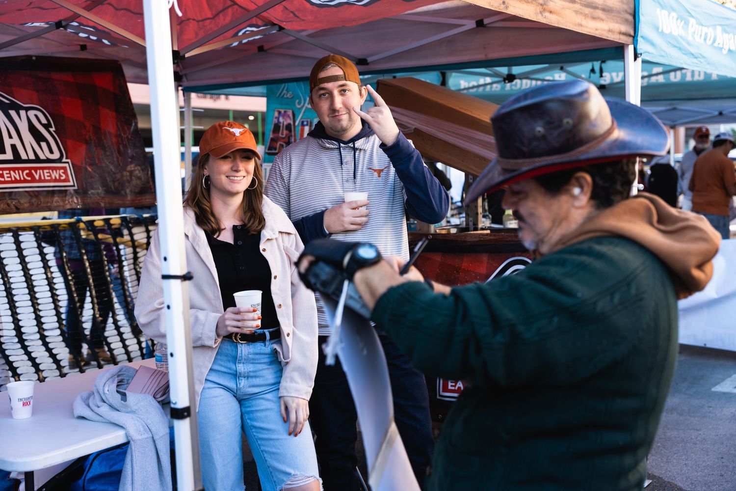 Group of attendees gathering at an outdoor vendor booth during a tailgate event.