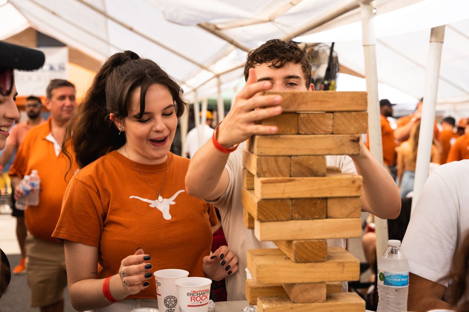 A group plays an intense game of Jenga at an outdoor gathering.