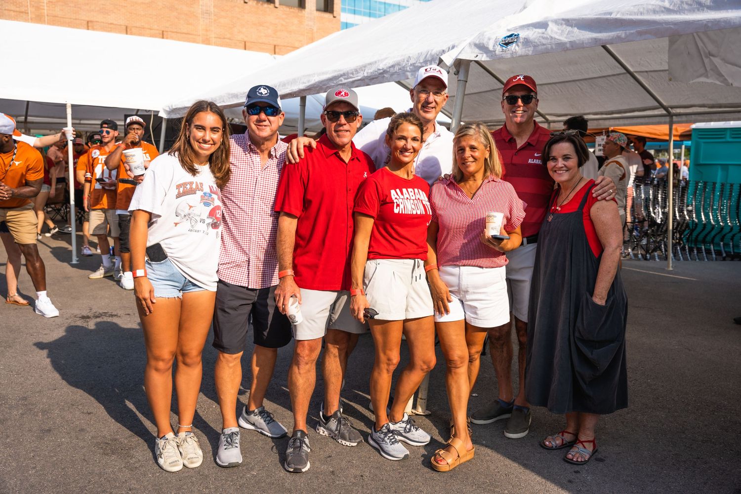 A group of fans wearing casual attire poses together at an outdoor sporting event or tailgate.