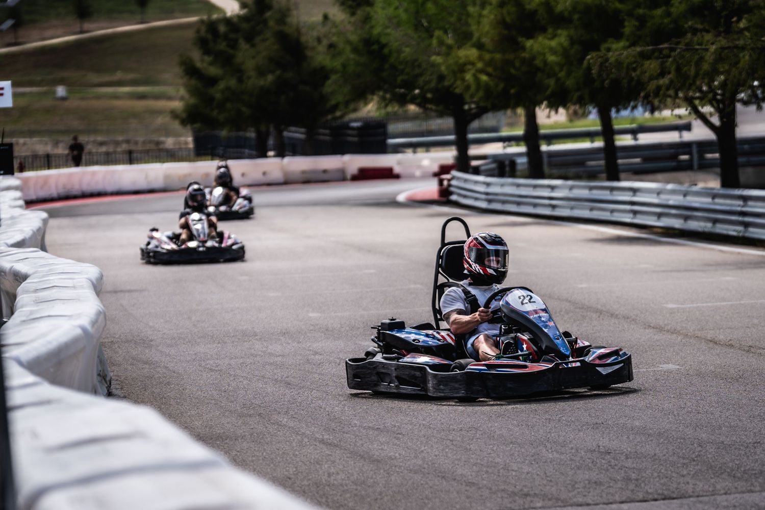 Multiple go-karts racing through a curved section of a professional karting track.