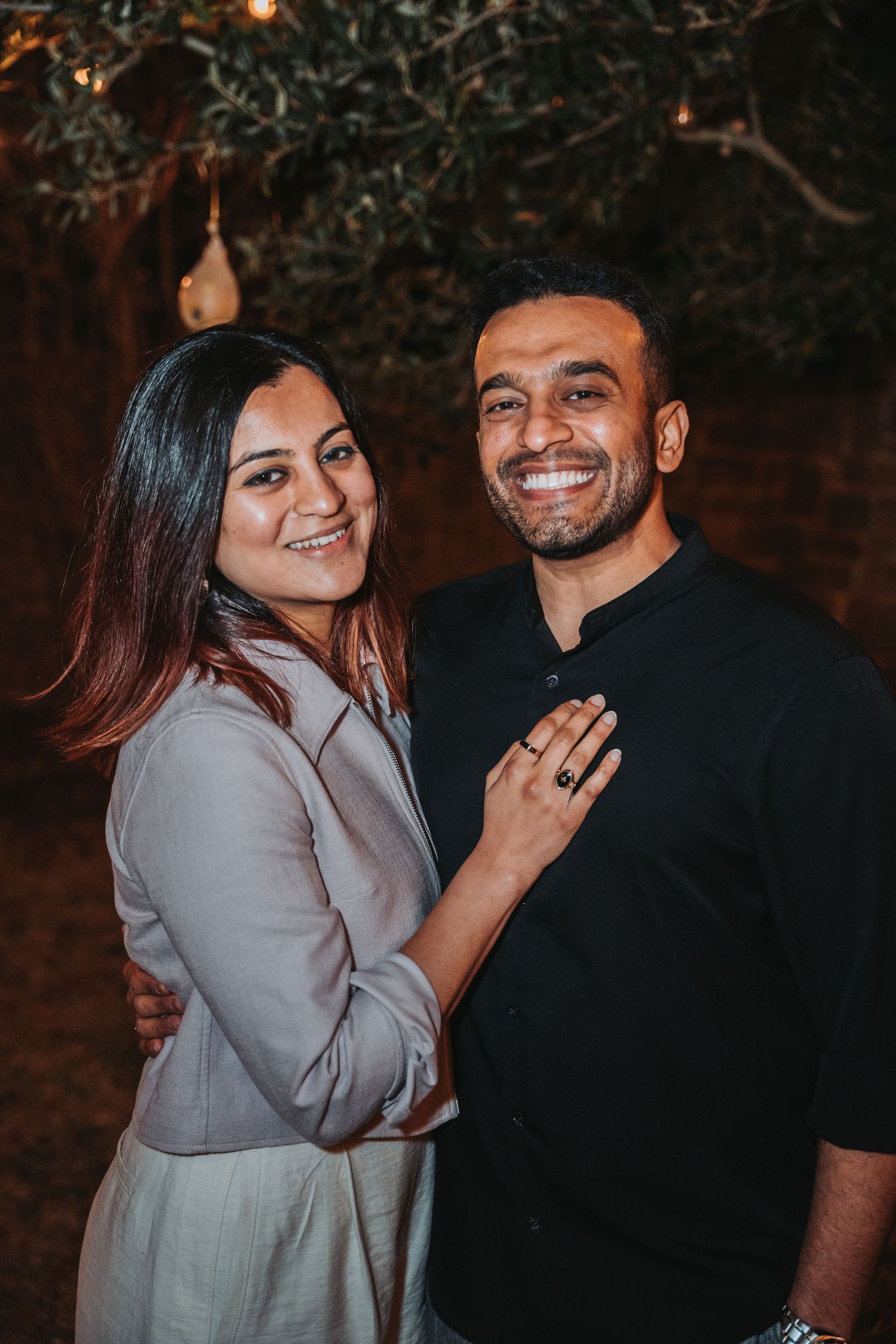 Couple sharing a romantic moment under string lights in an outdoor setting.
