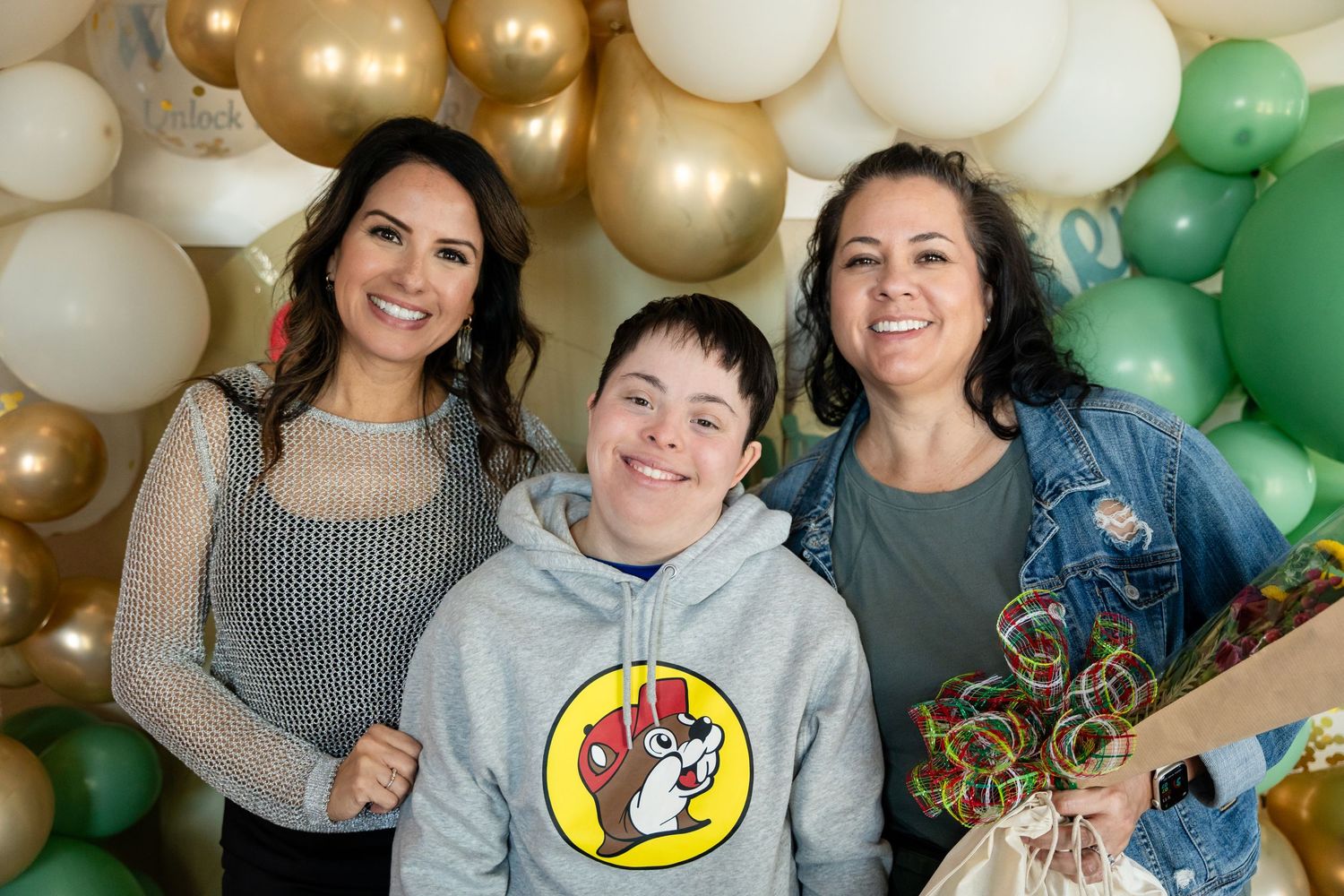 Group photo against balloon backdrop with white, gold and green color scheme.