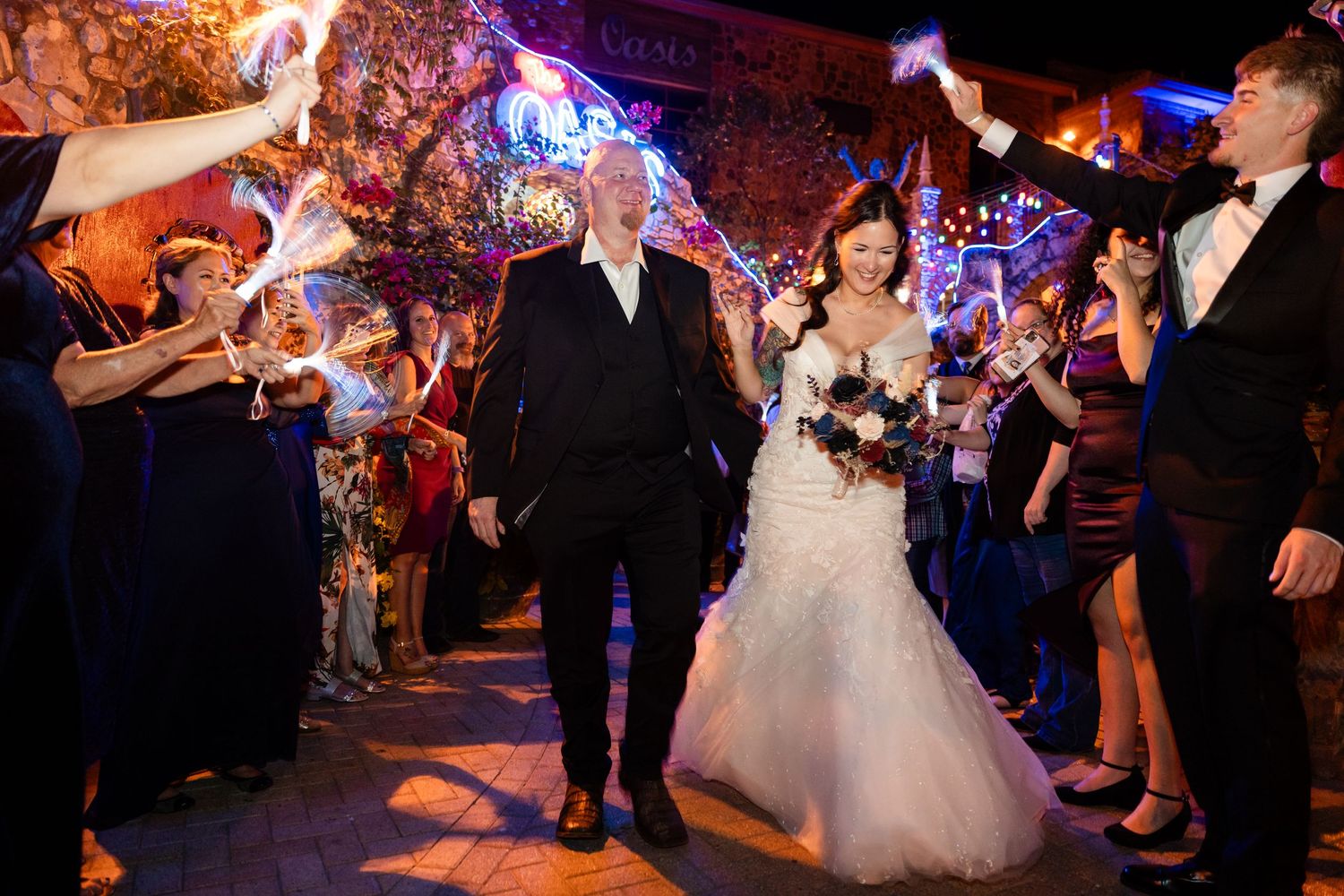 Wedding celebration exit with guests holding sparklers creating a magical tunnel effect at night.