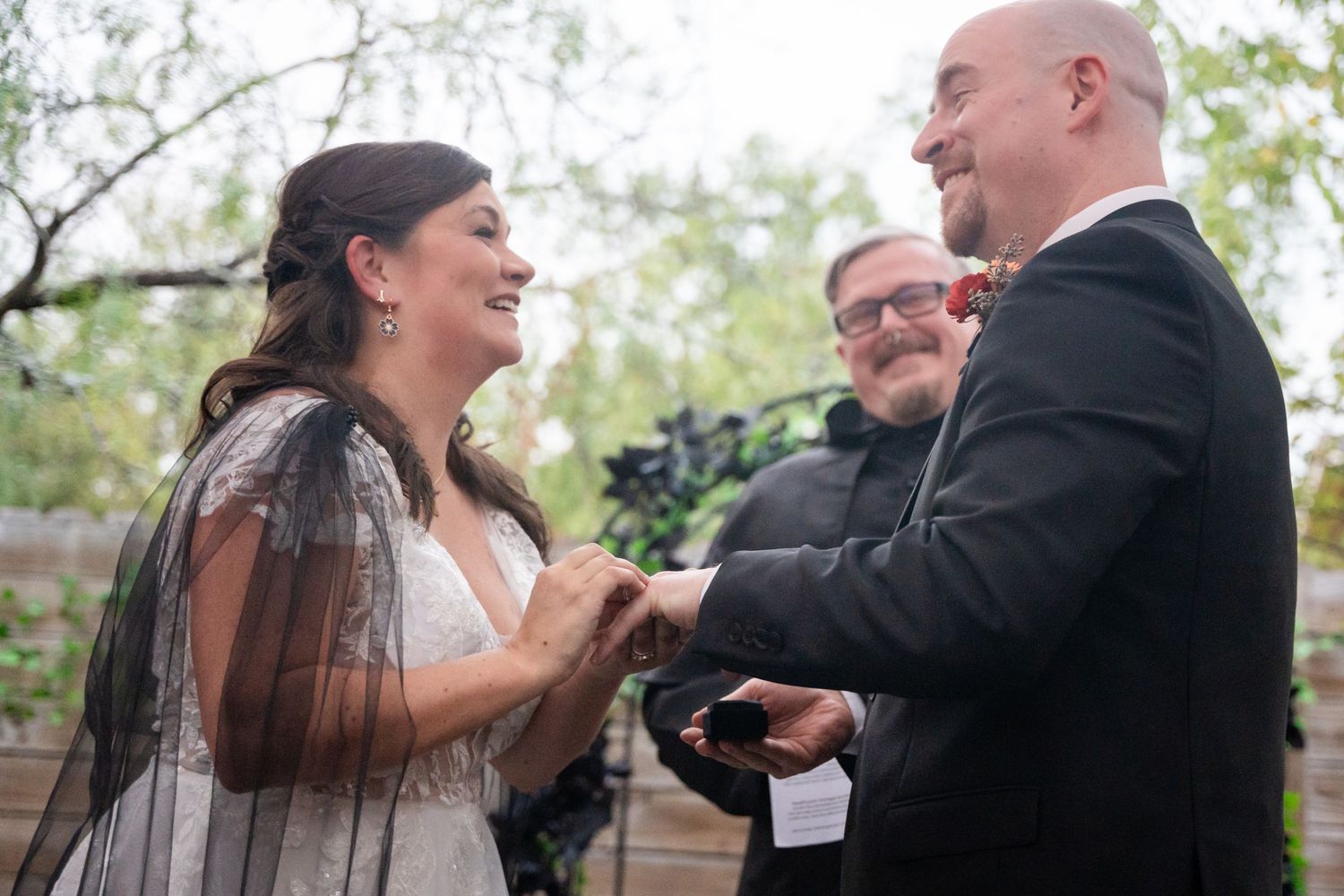 Intimate moment during outdoor wedding ceremony with natural backdrop.