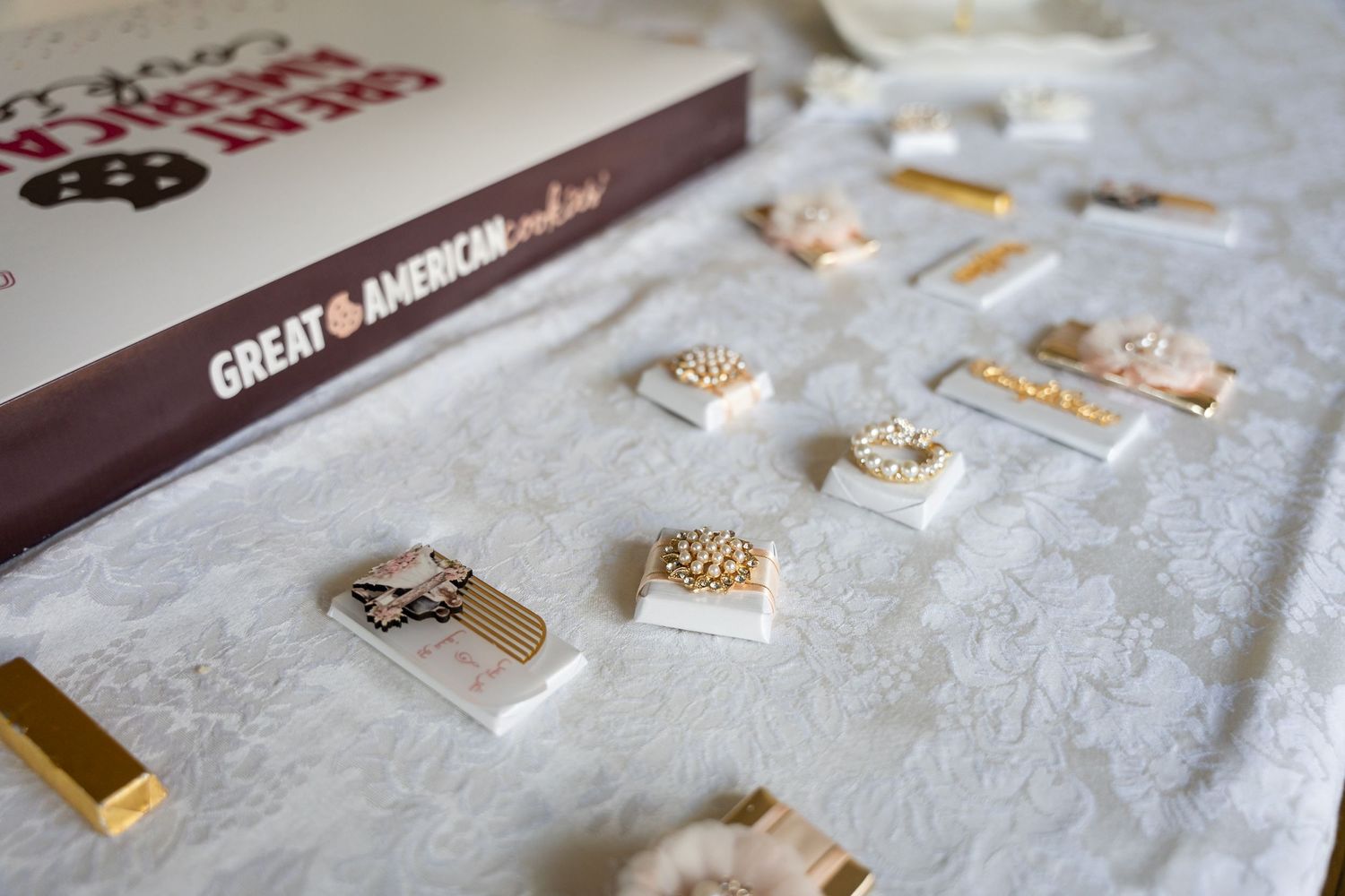 Collection of metallic lapel pins and accessories displayed on white textured fabric.