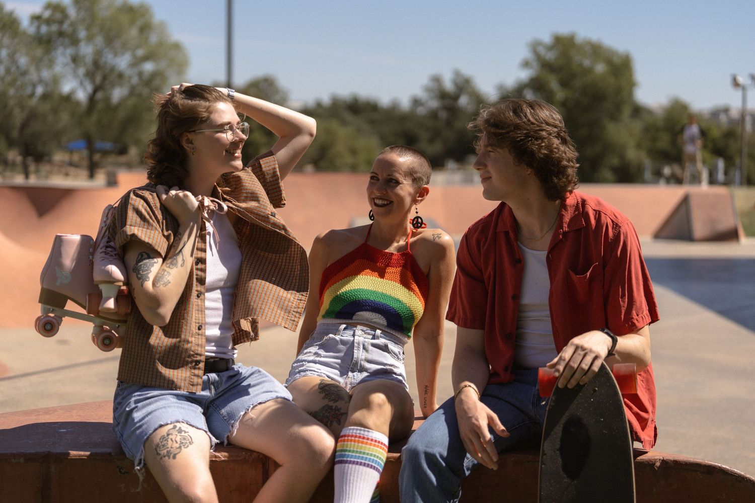 Three friends lounging and laughing together at a skateboarding park.