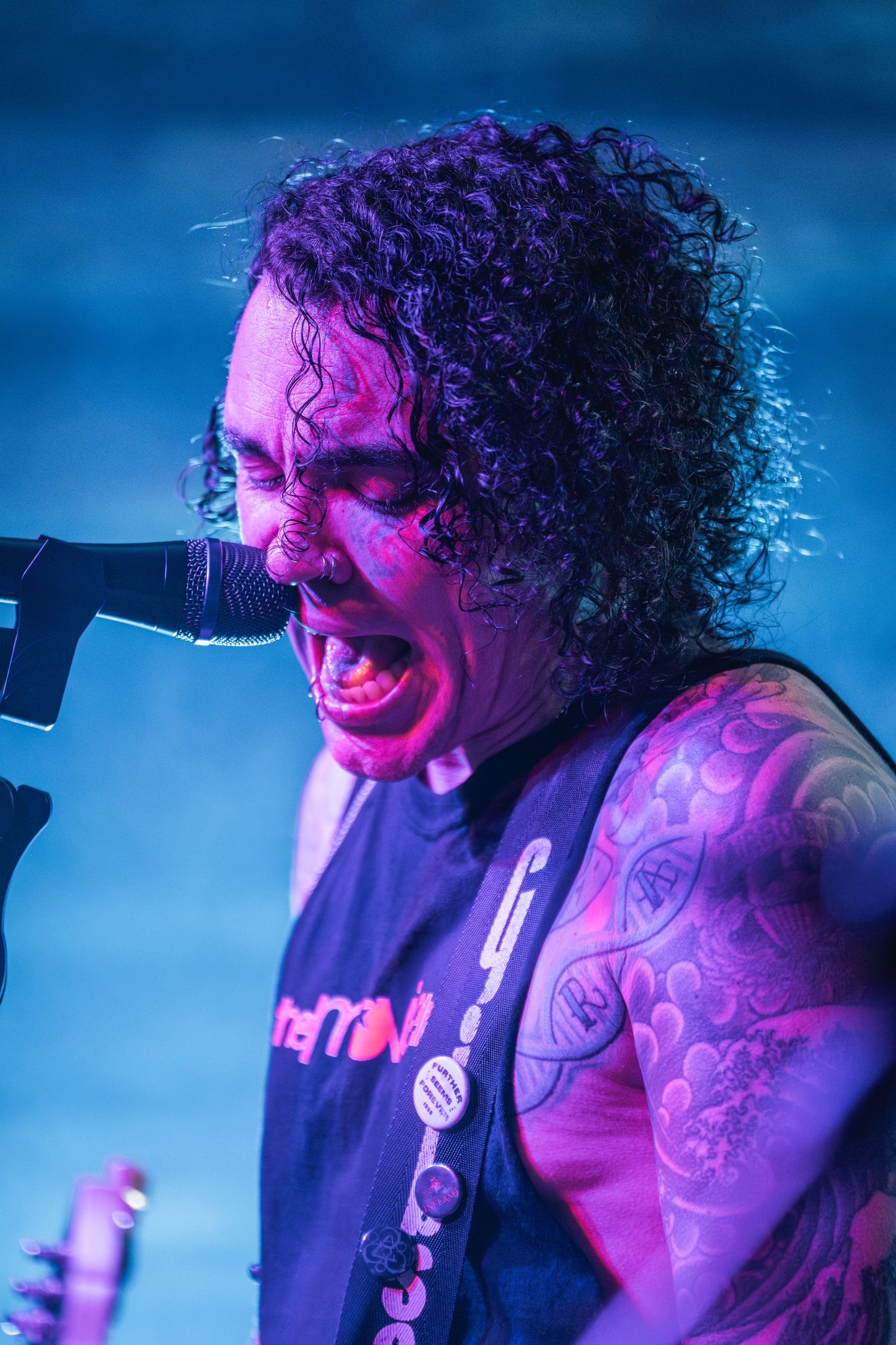 Performer sings emotionally into microphone under intense blue and purple stage lighting.