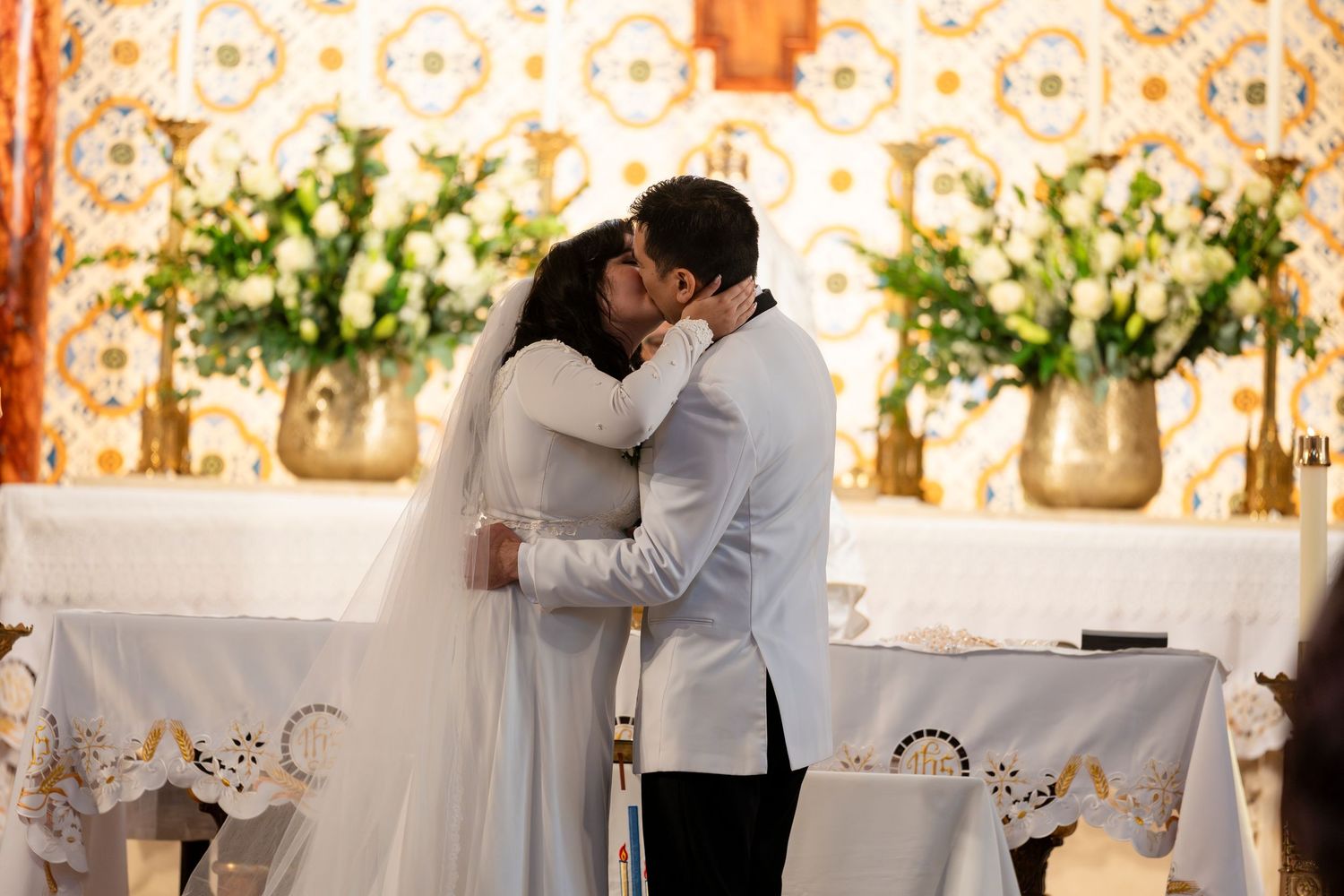 A series of romantic embraces captured during a wedding reception set against an elegant white floral backdrop.
