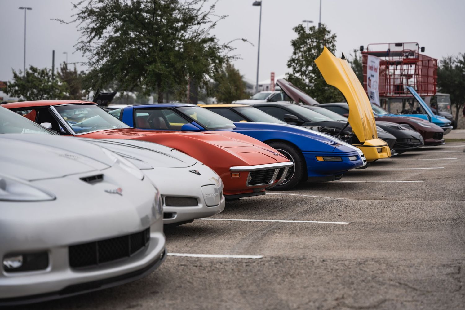 Row of colorful sports cars with open hoods displayed at a car show.