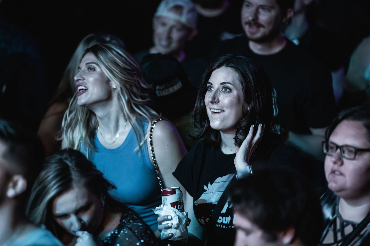 Enthusiastic fans enjoying a concert in the crowd with colorful lighting effects.
