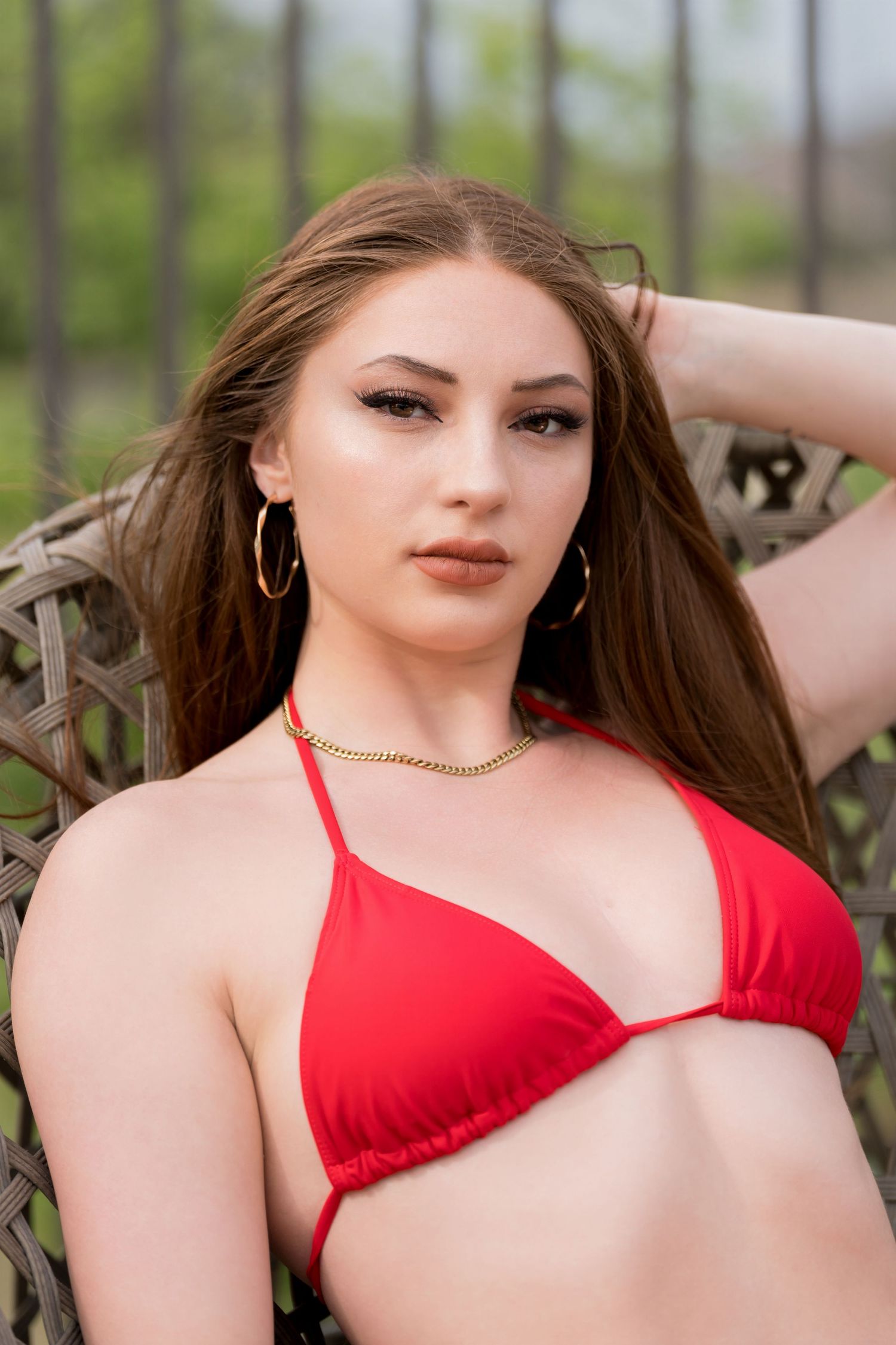 Person wearing red swimwear posing outdoors in natural lighting.
