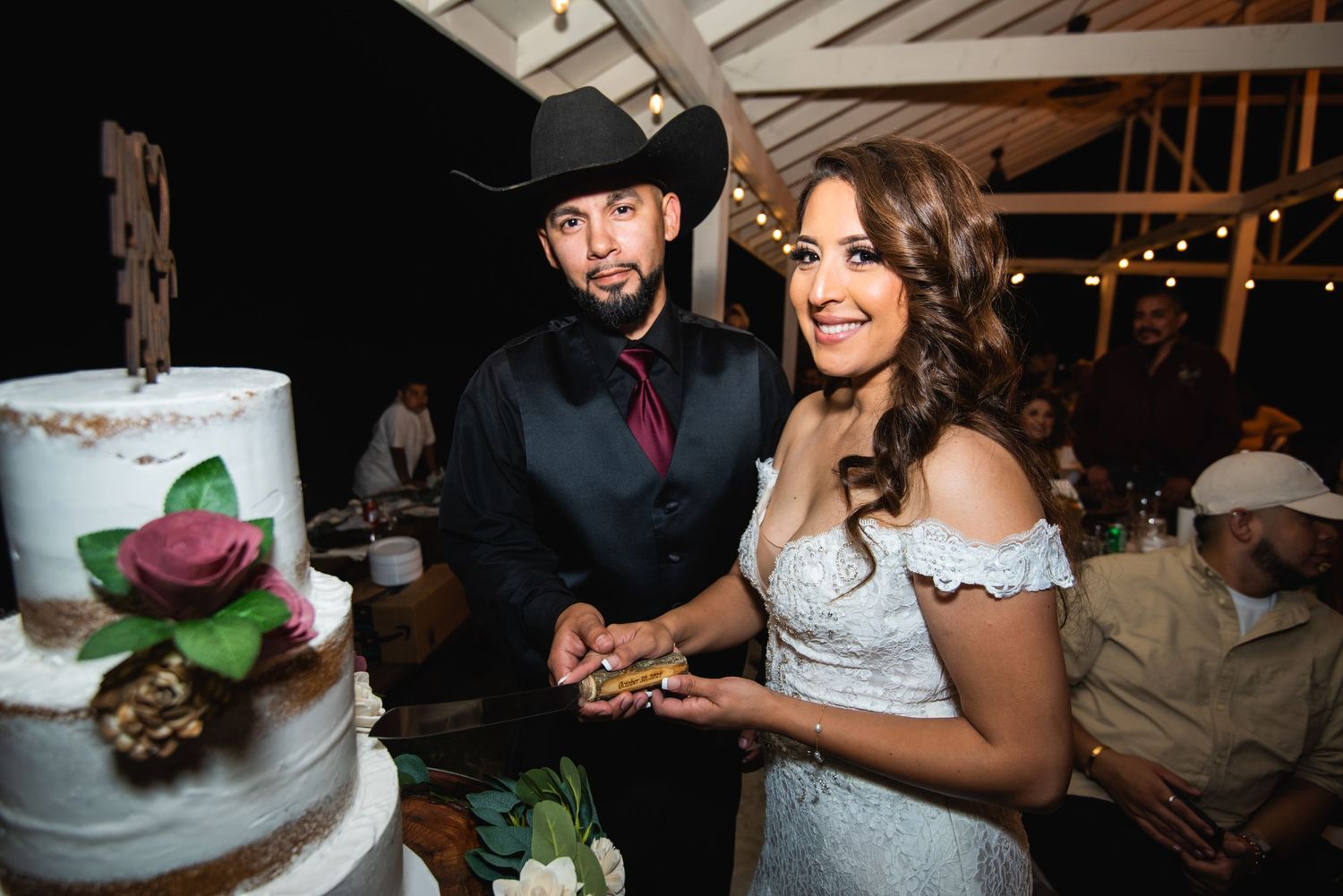 A couple shares a moment together while cutting their beautiful tiered wedding cake.