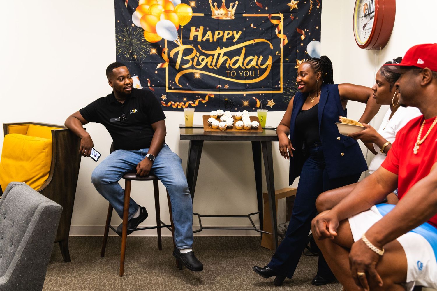 Group gathering in front of a festive birthday backdrop with gold and black decorations.