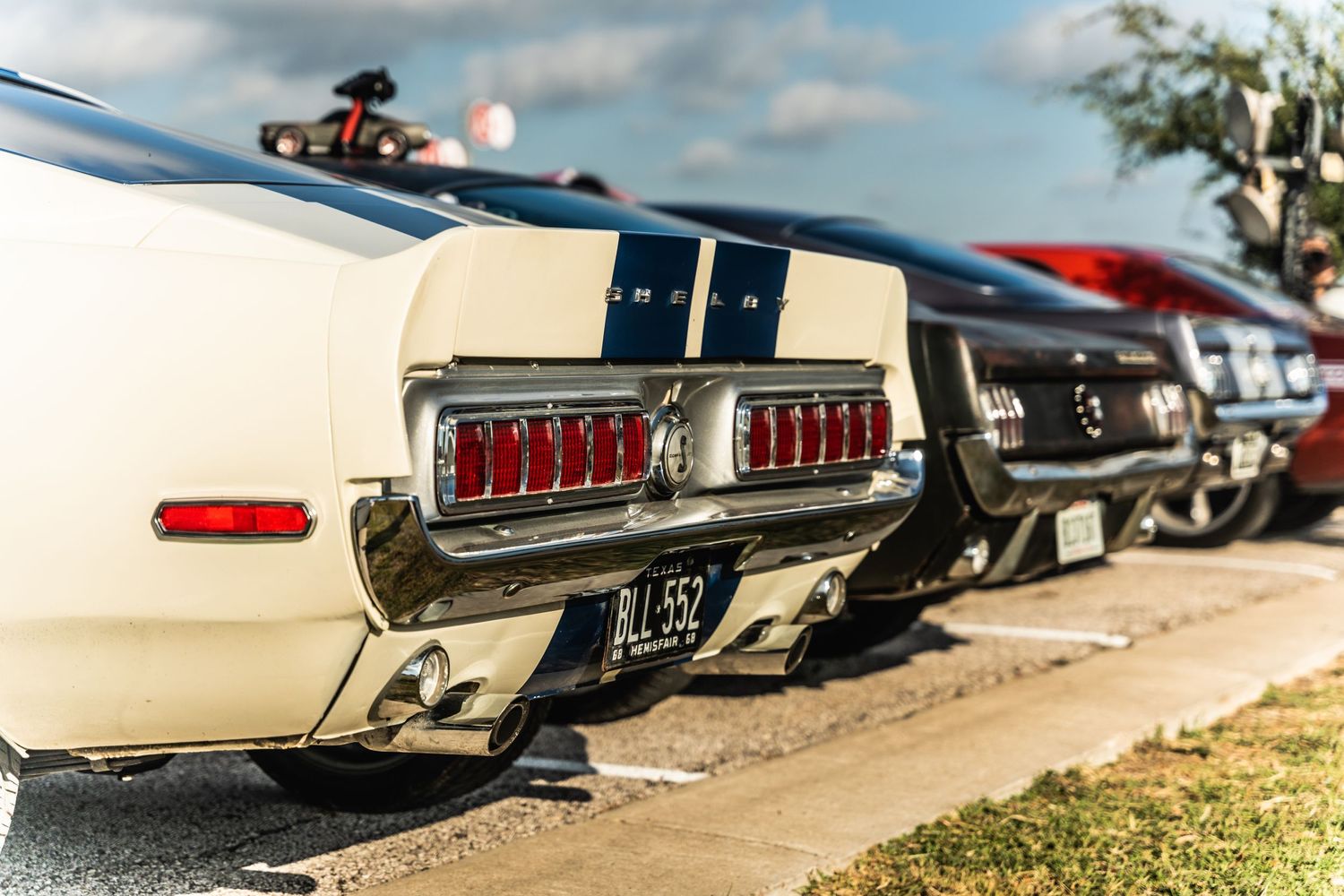 Classic Ford Mustang taillights in line at outdoor car show.