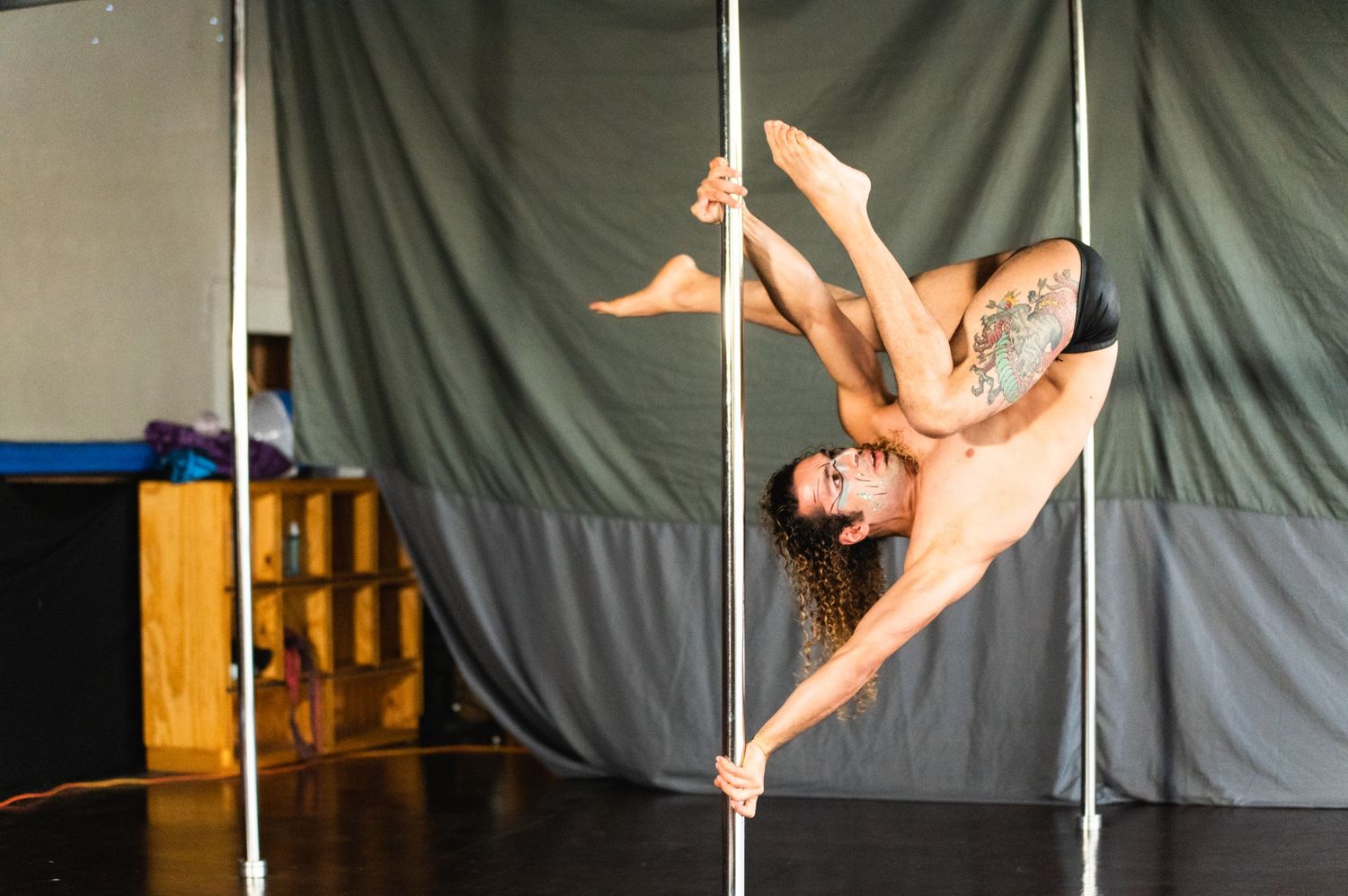 Two performers execute dramatic aerial duet on silver pole against theatrical backdrop.