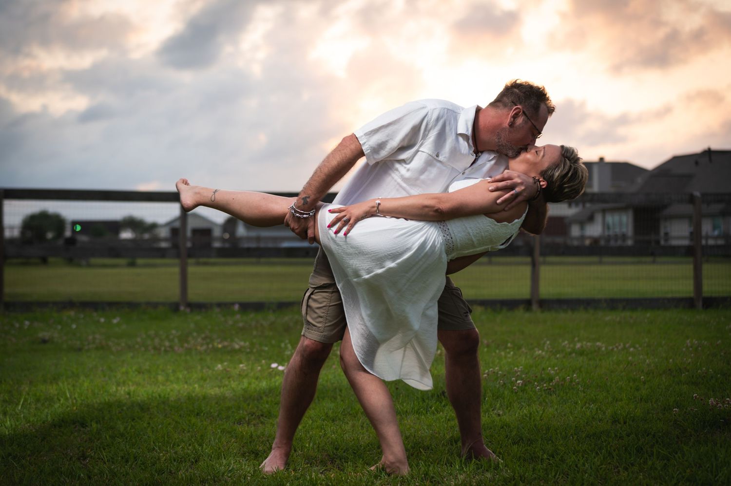 A romantic dip pose captured during sunset in a grassy field.