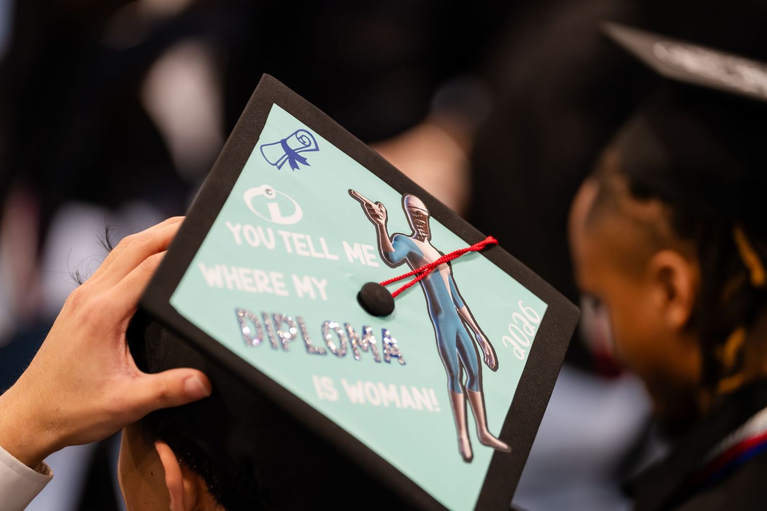 Decorated graduation cap with colorful anatomy illustration and text about diploma at a commencement ceremony.