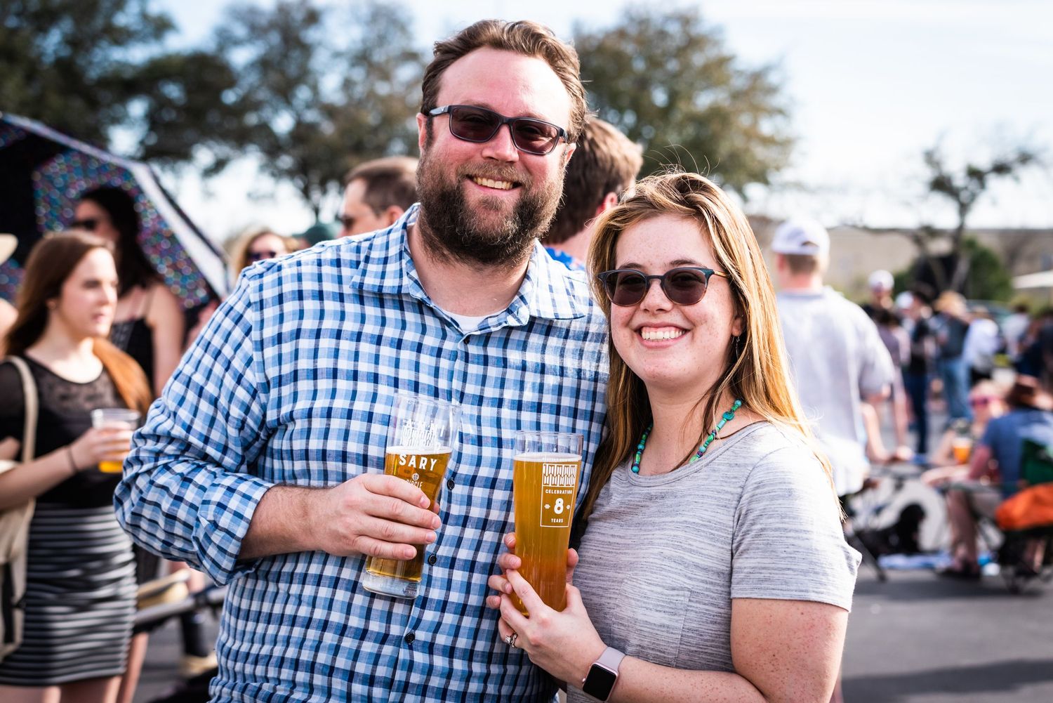 People enjoying drinks and socializing at an outdoor festival or gathering on a sunny day.
