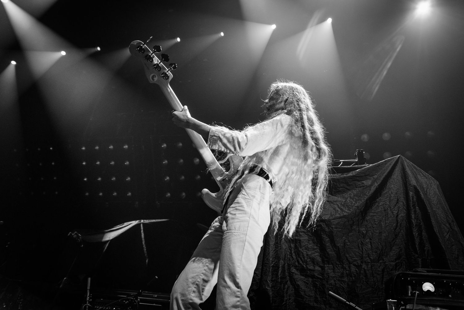 Black and white concert photo of a performer singing passionately on stage with dramatic lighting and shadows.