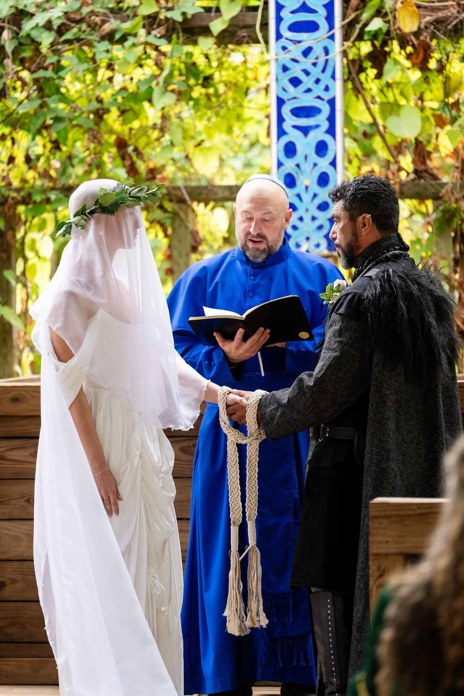 A sequence of four photos showing people in white, blue and black robes interacting in an outdoor garden setting.