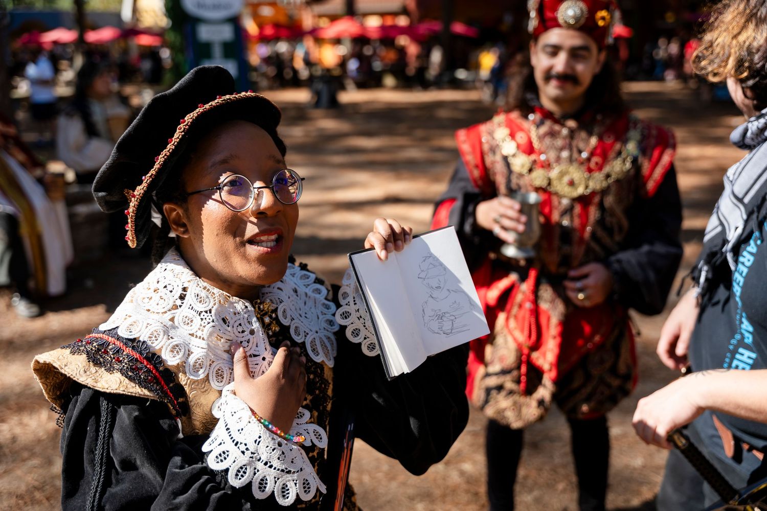A group of people dancing and celebrating at a Renaissance festival in period costumes and ruffled collars.
