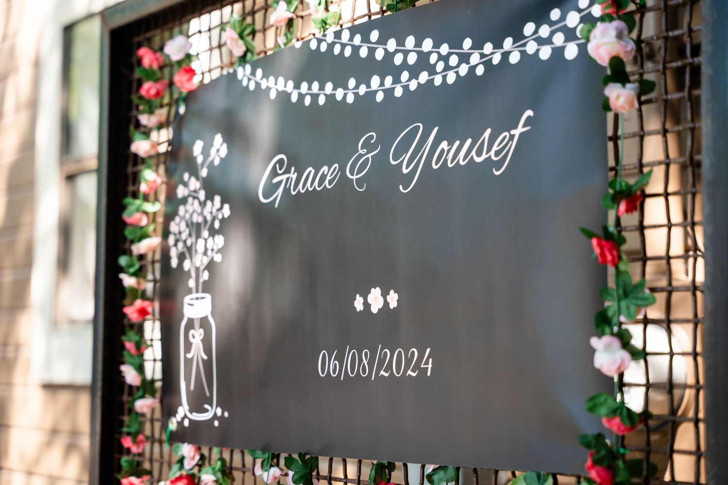 Wedding sign displaying 'Grace & Yousif' with date and decorative lights against a dark backdrop.