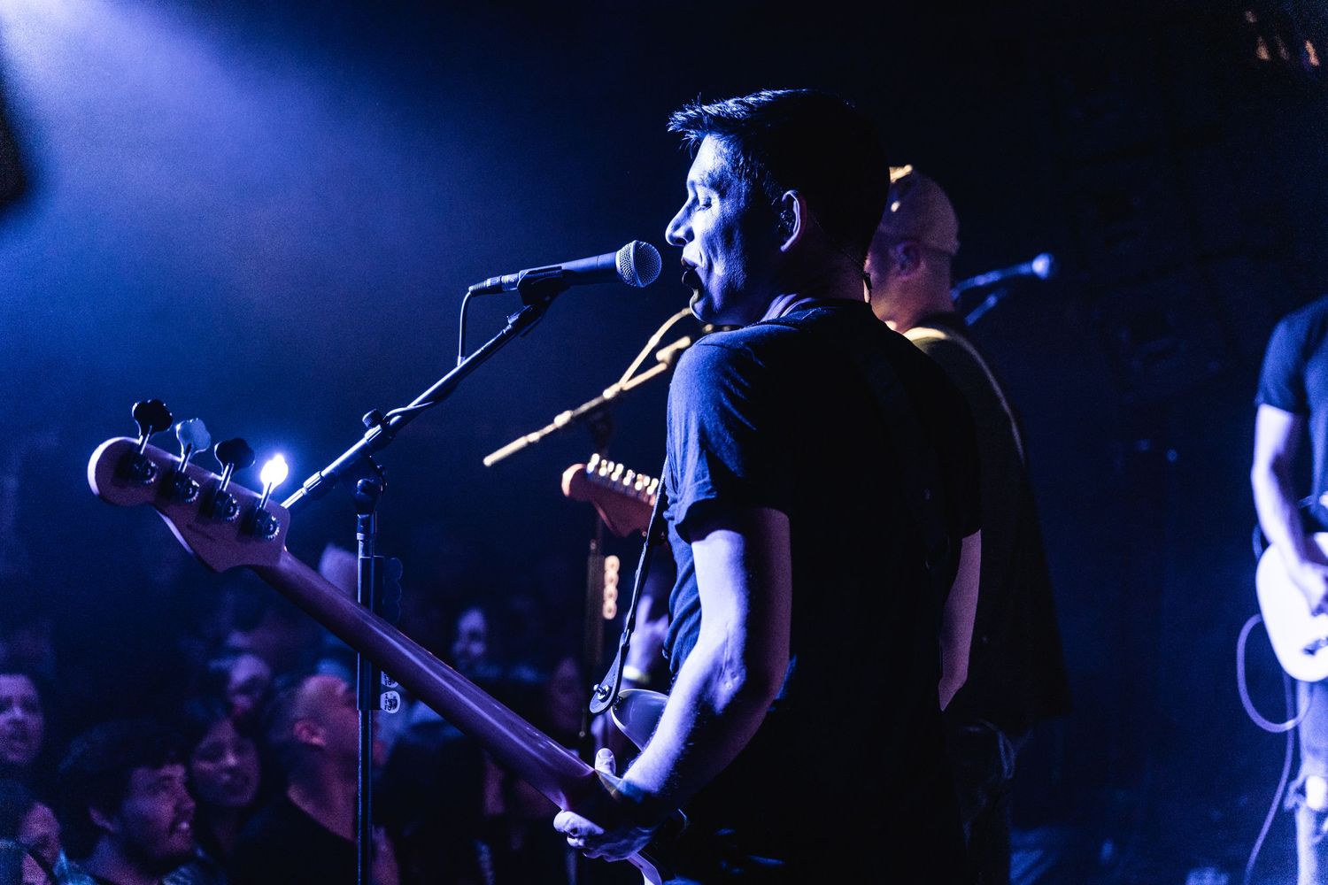 A musician performs with a guitar under dramatic blue stage lighting.