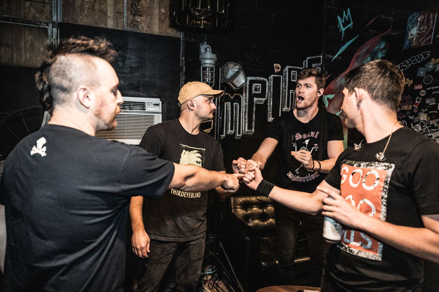 Musicians gathered backstage having an animated conversation in a casual setting.